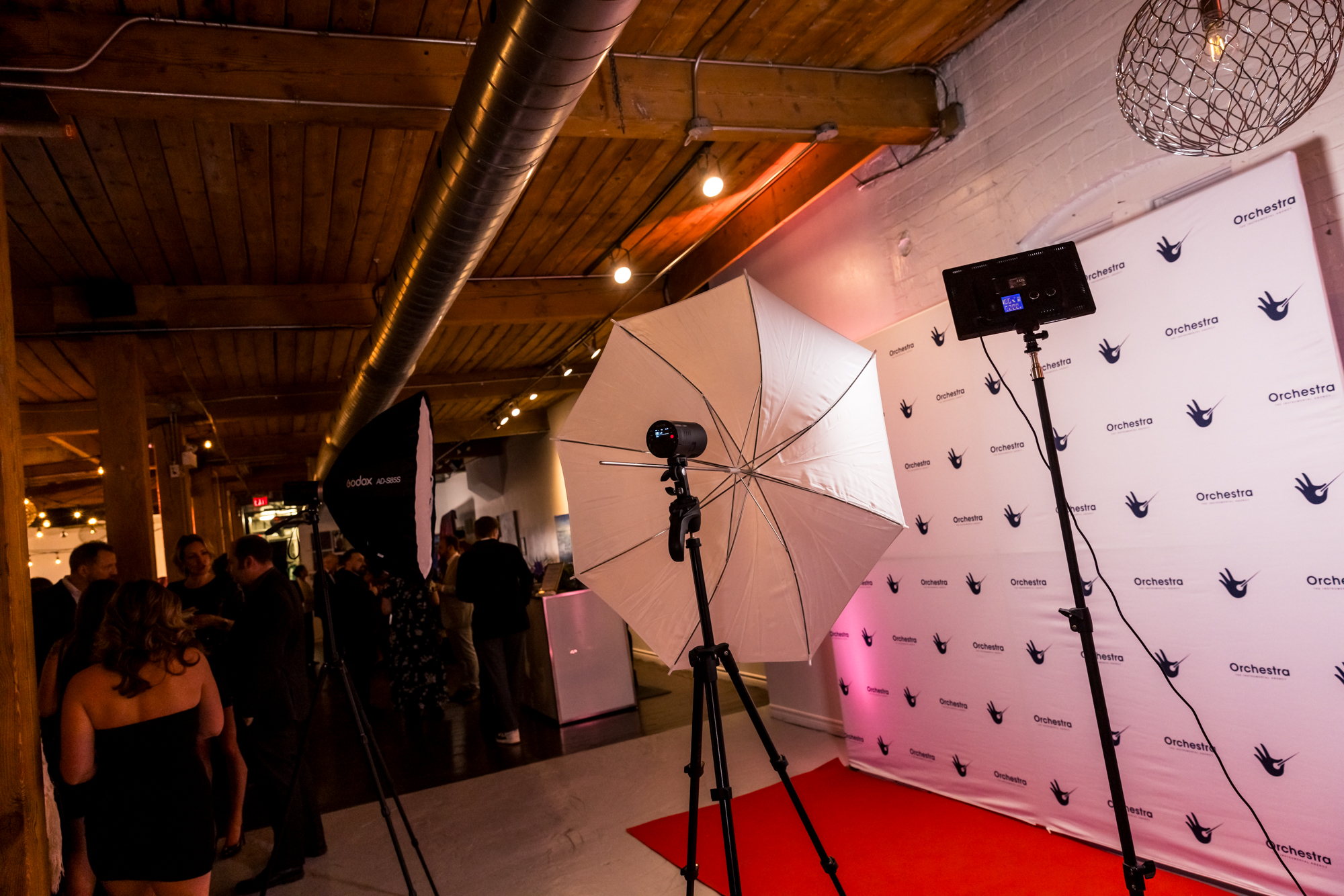 An event photo experience with studio lighting, a branded backdrop and guests gathering in a loft