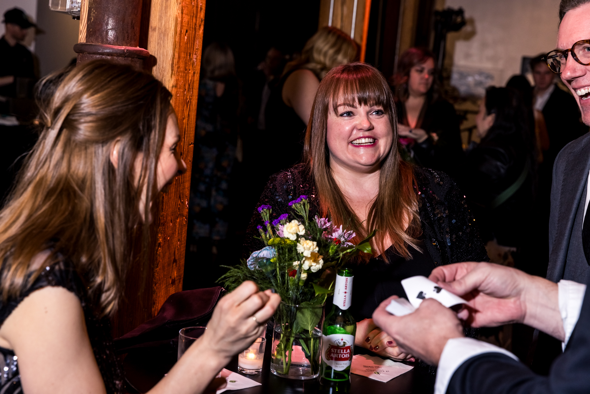 Guests enjoying a close-up card performance at a decorated cocktail table